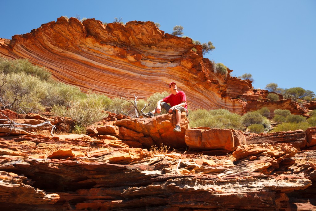 Man sitting bottom of colourful layered rock